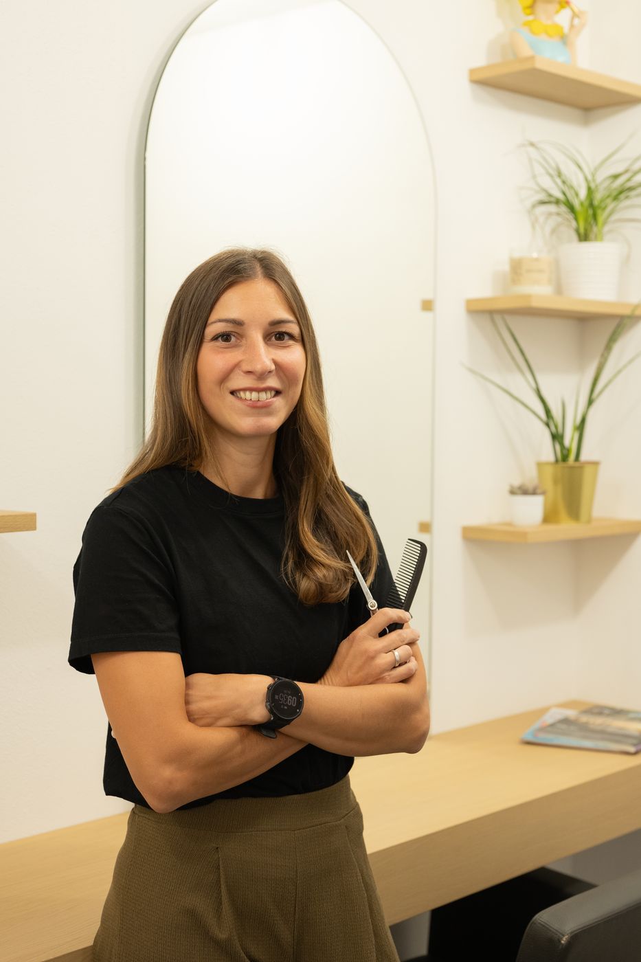 Gisi mit Schere vor dem Bogenspiegel in ihrem Salon